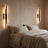 A left- and right-facing pair of slim sconces flanking a linen bed