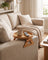 Sofa arm tray clipped onto a linen sofa arm in a warm living room with a mug and remote