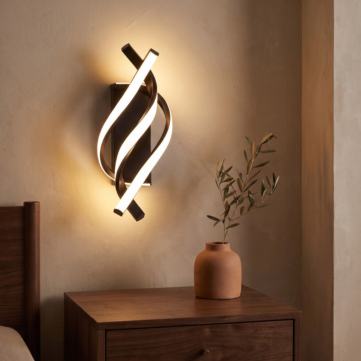 Spiral LED wall sconce lit above a walnut nightstand in evening light