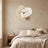 Three Pebble Silent Wall Clock hanging on a limewash plaster wall above a bed with oatmeal linen bedding.