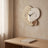 Three Pebble Silent Wall Clock hanging on a plaster wall above a white oak desk in daylight.