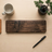 Wooden cutting board on a wooden surface with a mug, pen, and small plant.