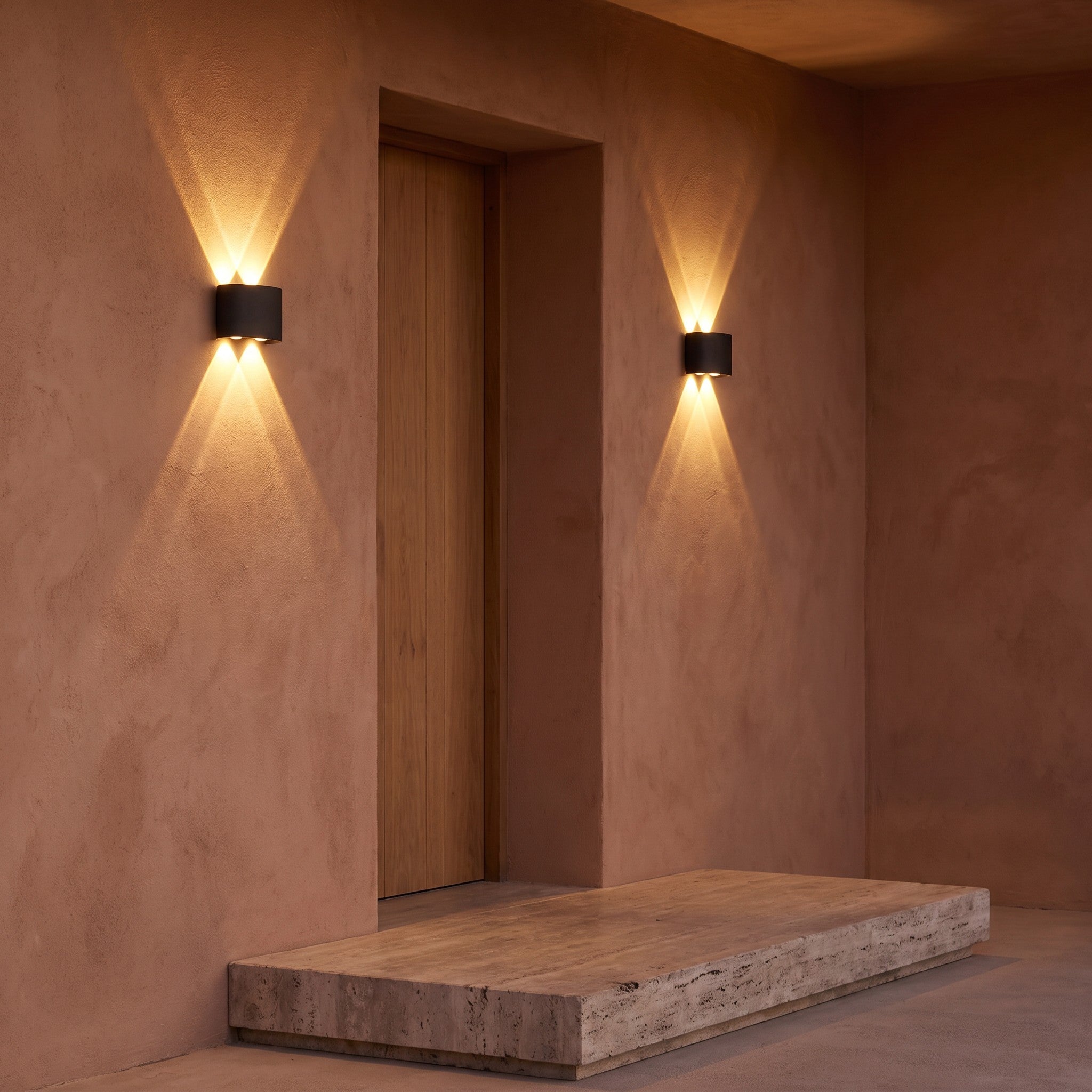 A pair of up-down wall lights either side of a porch doorway at dusk