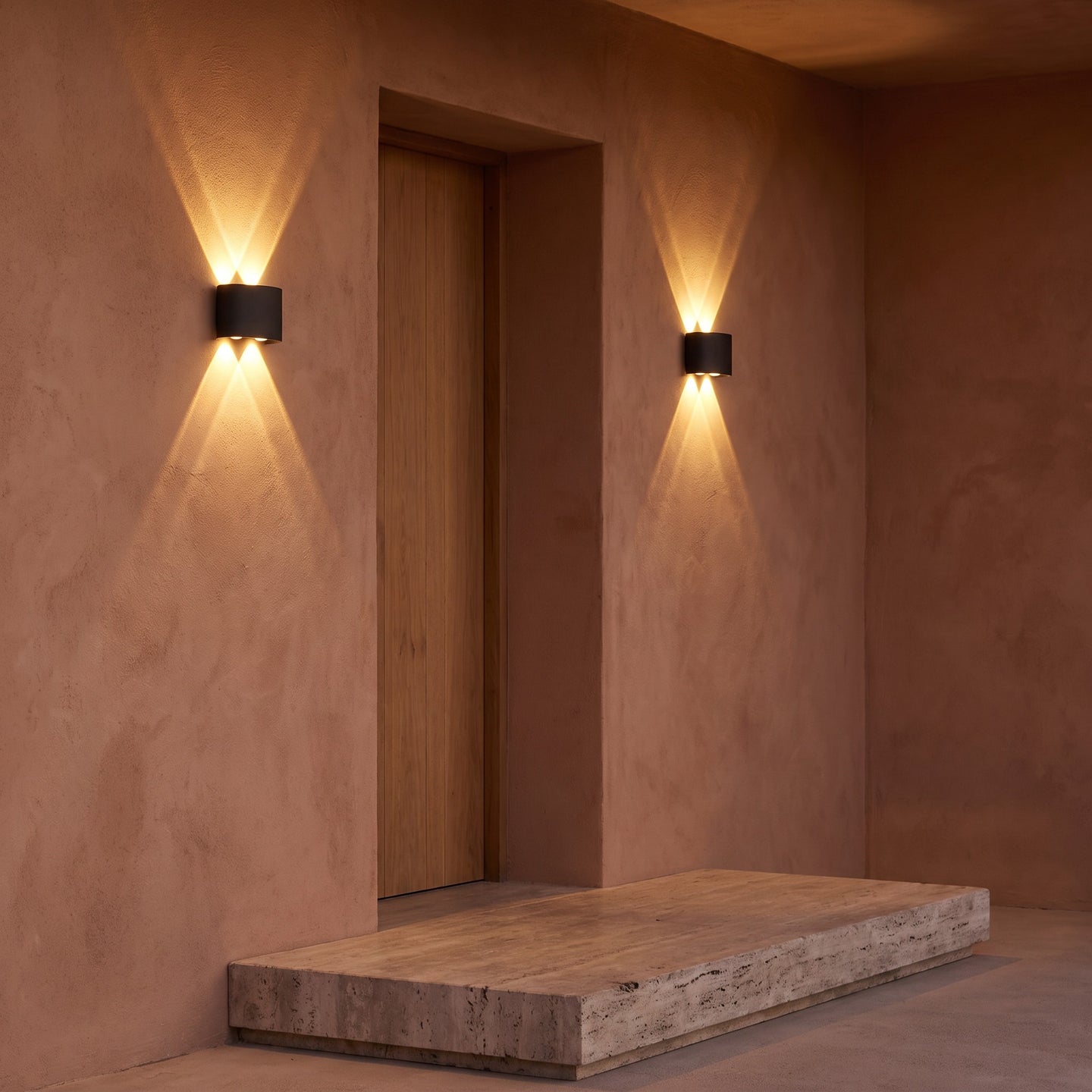 A pair of up-down wall lights either side of a porch doorway at dusk