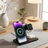 Wireless charging stand with smartphone, smartwatch, and headphones on a desk.