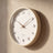 Cream Wood Frame Silent Wall Clock seen from a low angle, showing the frame's depth and its shadow on the plaster wall.